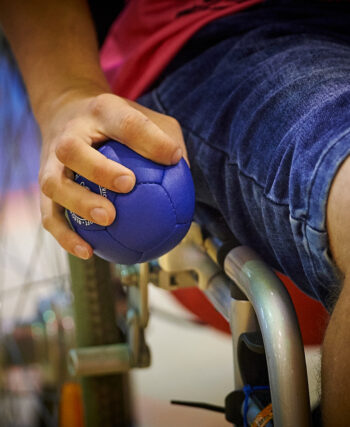 Grupa osób z niepełnosprawnościami trenuje boccię w hali sportowej Politechniki Poznańskiej w Poznaniu.