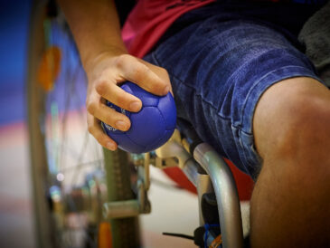 Grupa osób z niepełnosprawnościami trenuje boccię w hali sportowej Politechniki Poznańskiej w Poznaniu.